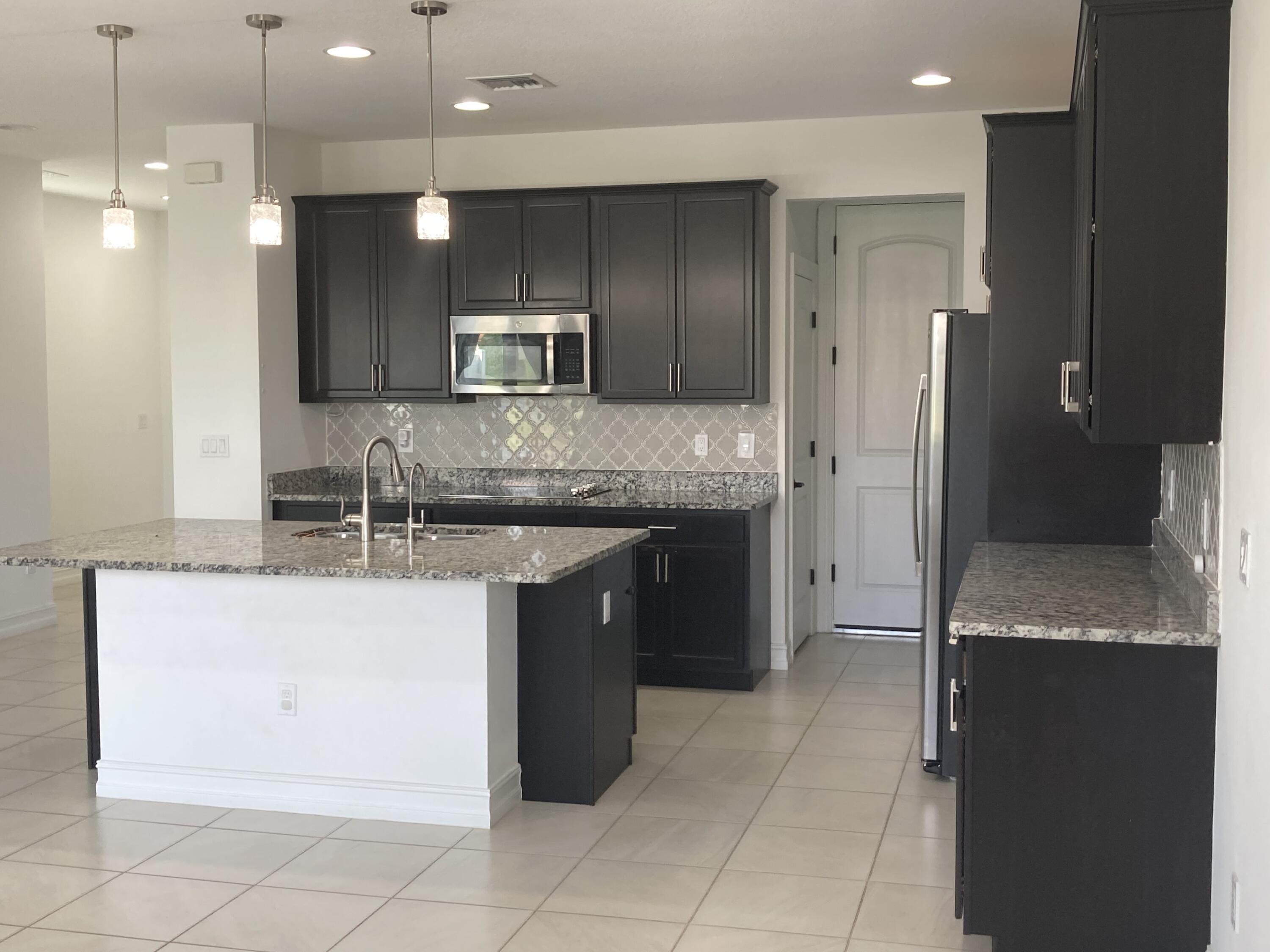 10092 Brickhill Drive Boca Raton, FL 33428 - Photo 5 of 42 a kitchen with kitchen island granite countertop a sink a counter top space appliances and cabinets