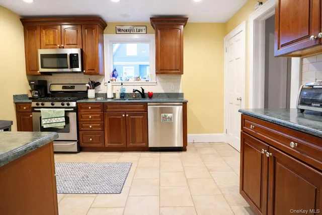a kitchen with stainless steel appliances granite countertop a stove a sink and a microwave
