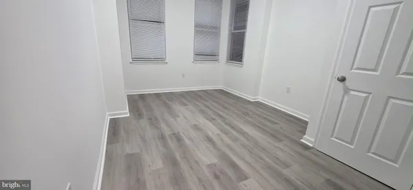 a view of an empty room with wooden floor and entrance