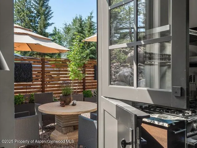 a balcony with table and chairs and potted plants