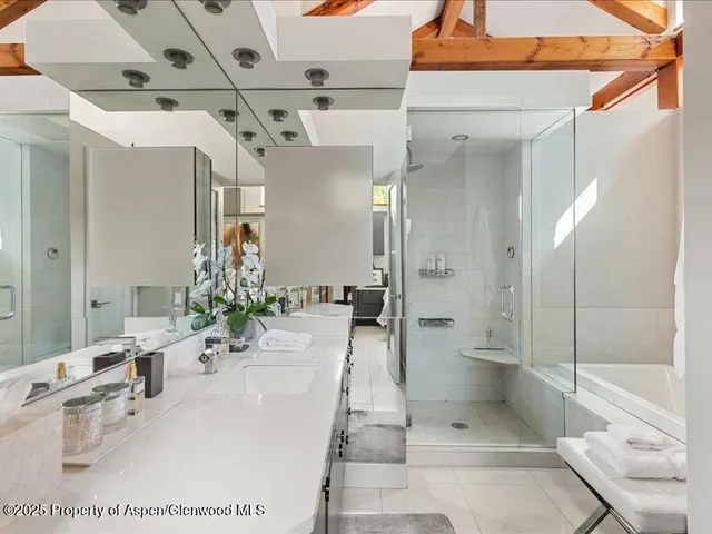 a bathroom with a tub shower sink and mirror