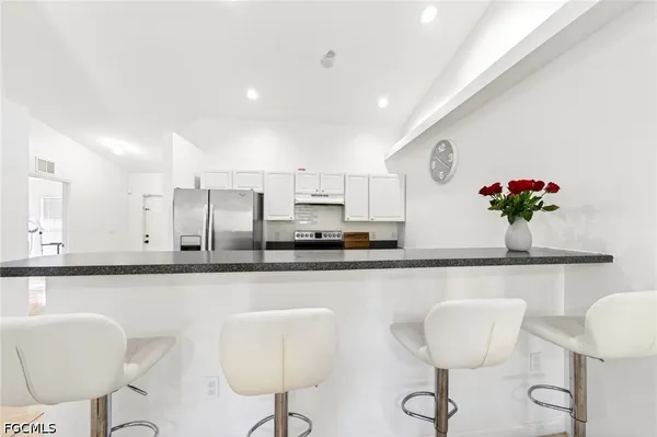 a kitchen with stainless steel appliances granite countertop a dining table chairs and a refrigerator