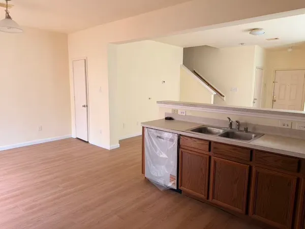 a view of an empty room with wooden floor and stairs