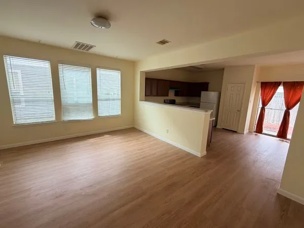 a view of an empty room with wooden floor and stairs