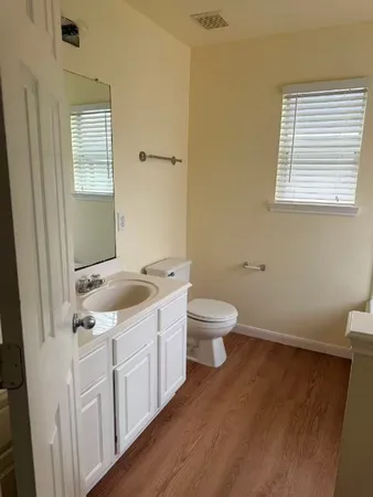 a view of an empty room with wooden floor and windows