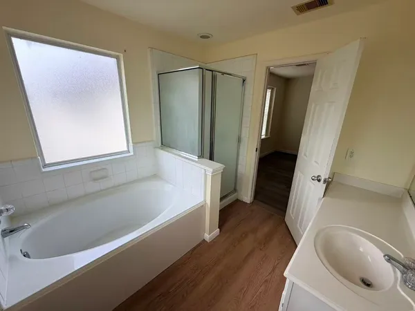 a view of a hallway with wooden floor and a bathroom