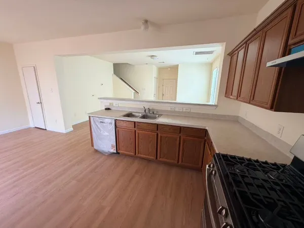 a view of a kitchen with stainless steel appliances wooden floor and a cabinet