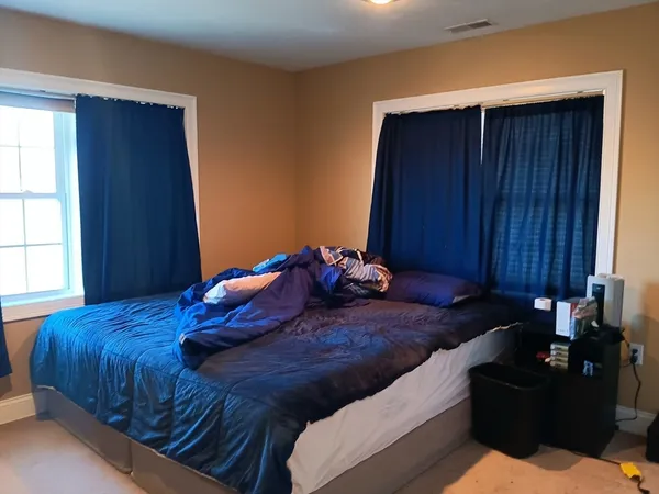 a bed sitting in a bedroom next to a window and a chair