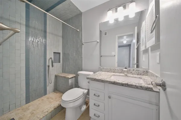 a bathroom with a granite countertop toilet sink and mirror