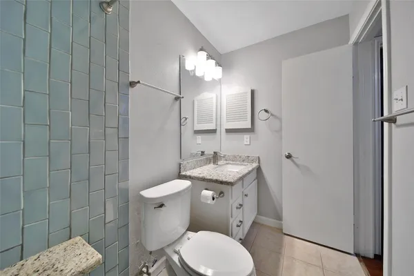 a bathroom with a granite countertop toilet a sink and a mirror