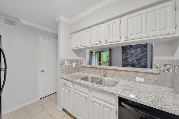 a kitchen with granite countertop a sink and a white cabinets