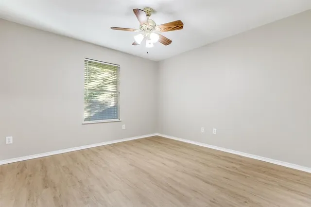 an empty room with a window and a fan
