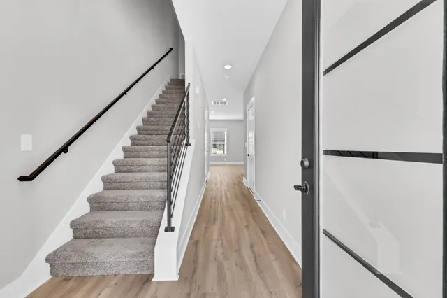 a view of staircase with wooden floor and white walls