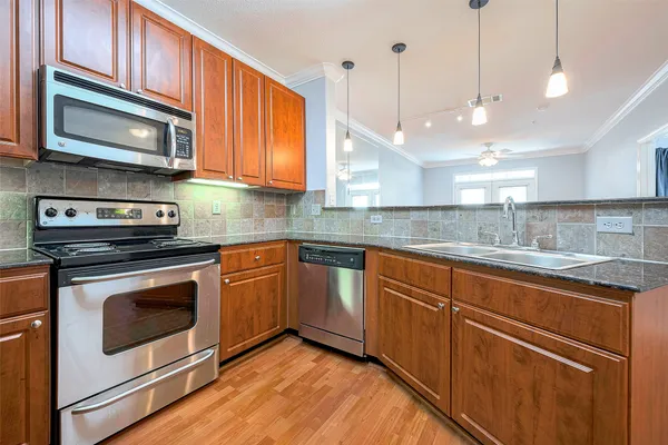 a kitchen with stainless steel appliances granite countertop a refrigerator a stove and a sink with wooden floor