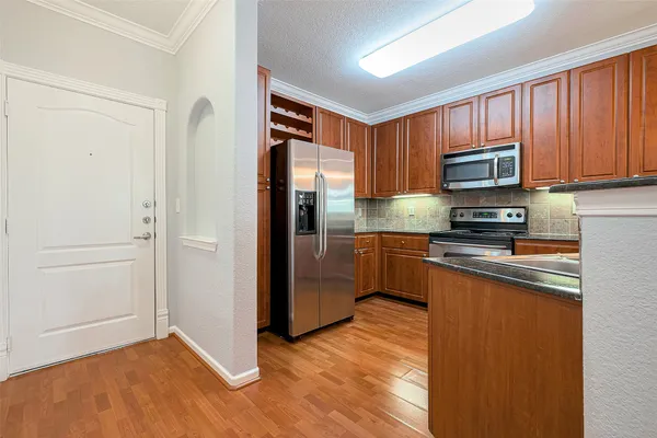 a kitchen with stainless steel appliances granite countertop wooden cabinets a stove a sink and a microwave