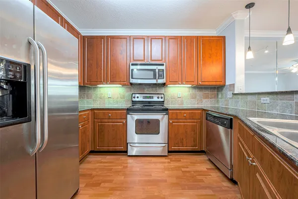 a kitchen with stainless steel appliances granite countertop a sink a stove a microwave and wooden floors