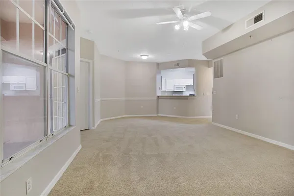 an empty room with chandelier fan and windows