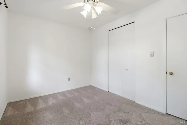 an empty room with a ceiling fan and a window