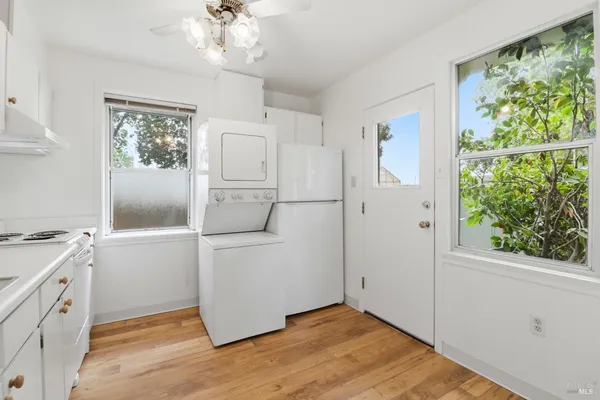 a view of an empty room with wooden floor and windows