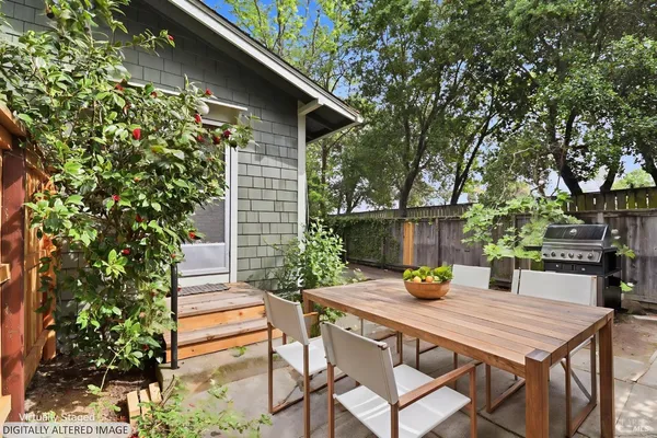 a pathway of a house with potted plants and a large tree