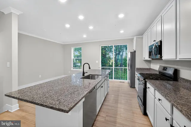 a kitchen with granite countertop kitchen island stainless steel appliances a sink stove and cabinets
