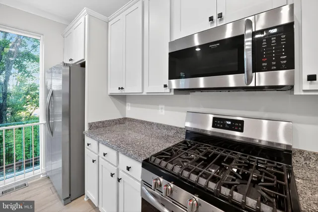 a kitchen with stainless steel appliances kitchen island granite countertop a stove and a microwave