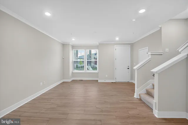 a view of an empty room with wooden floor and stairs