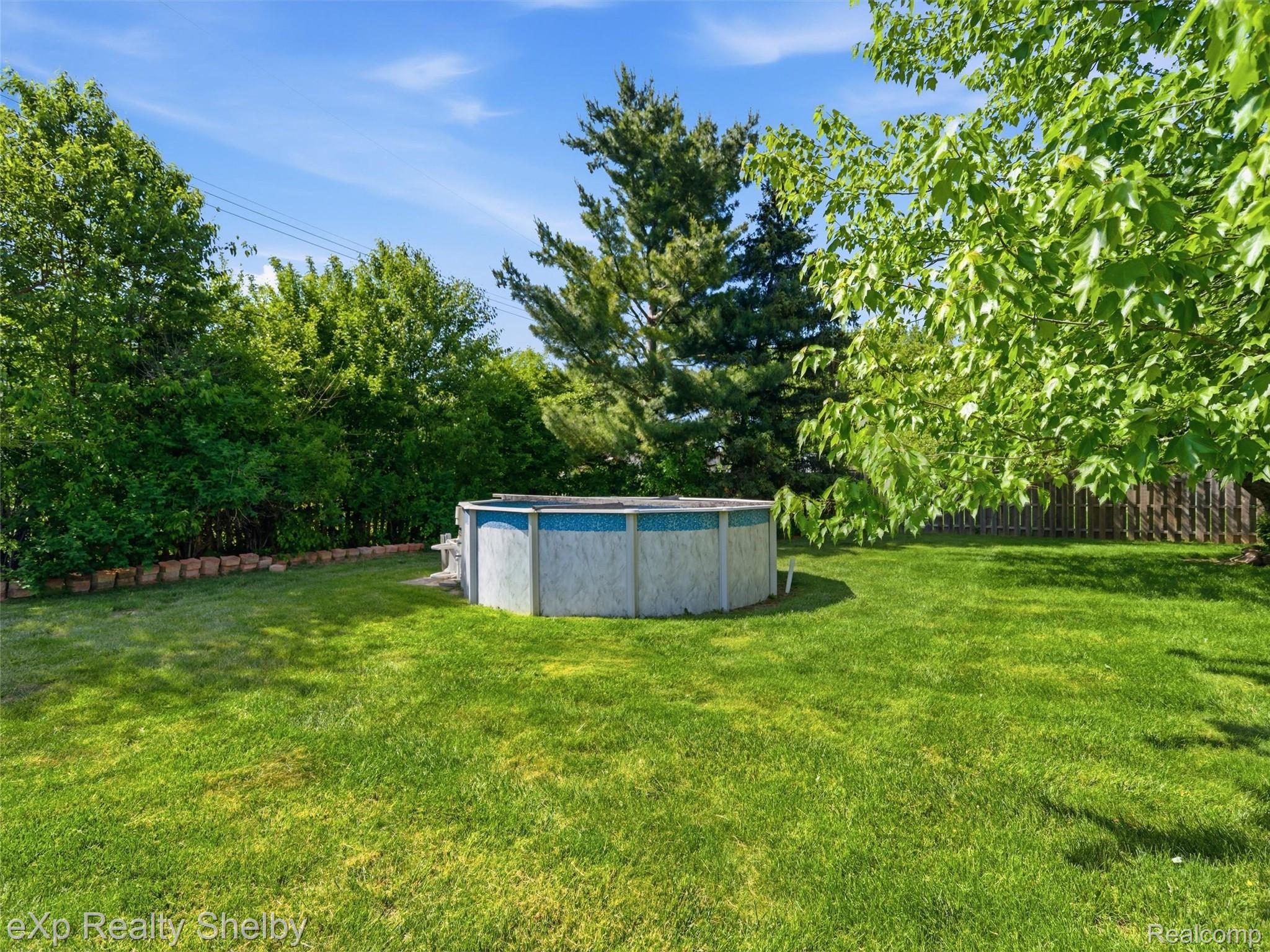 4154 Union Street Dryden, MI 48428 - Photo 36 of 41 Spacious backyard featuring an above-ground pool, expansive green lawn, mature trees, and a wood privacy fence