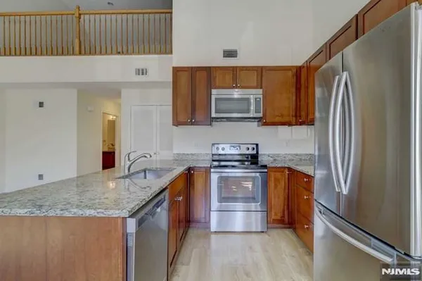 a kitchen with stainless steel appliances granite countertop a refrigerator a stove a sink and a microwave