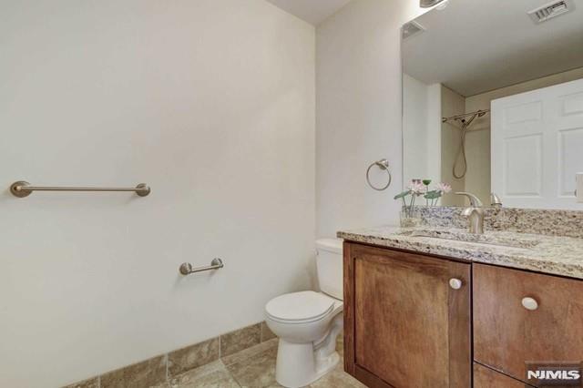 269 Main Street, Unit 2 Little Ferry, NJ 07643 - Photo 17 of 37 a bathroom with a granite countertop toilet a sink and mirror