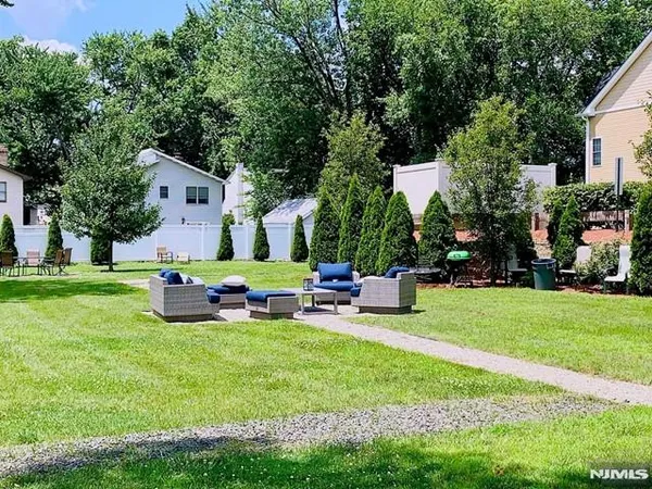 a view of backyard with table and chairs and potted plants and large trees