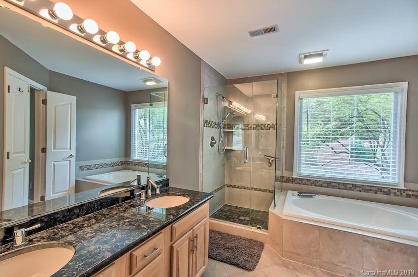 9731 Deer Spring Lane Charlotte, NC 28210 - Photo 9 of 26 a bathroom with a granite countertop tub a sink and a large mirror