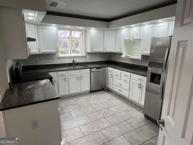 a kitchen with stainless steel appliances granite countertop a sink stove and refrigerator
