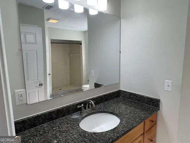 a bathroom with a granite countertop sink and a mirror