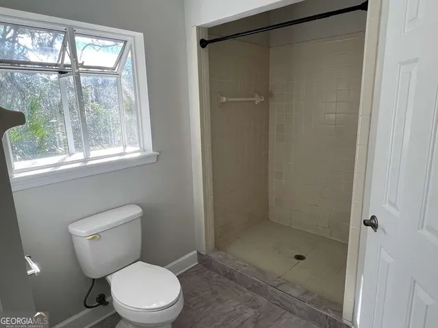 a bathroom with a toilet a shower and a window