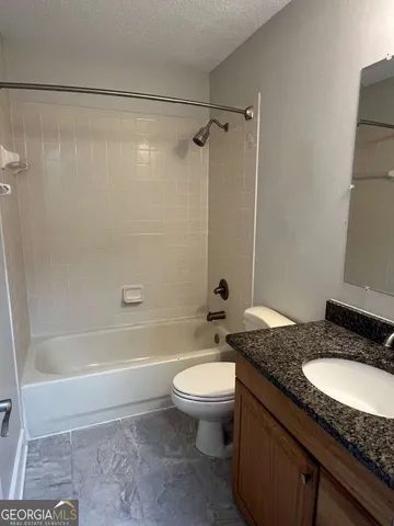 a bathroom with a granite countertop sink toilet and shower