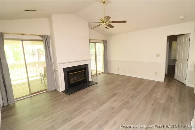 a view of empty room with wooden floor and fireplace