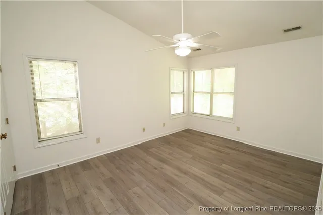 an empty room with wooden floor and windows