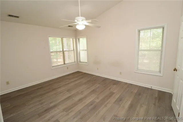 an empty room with wooden floor and windows