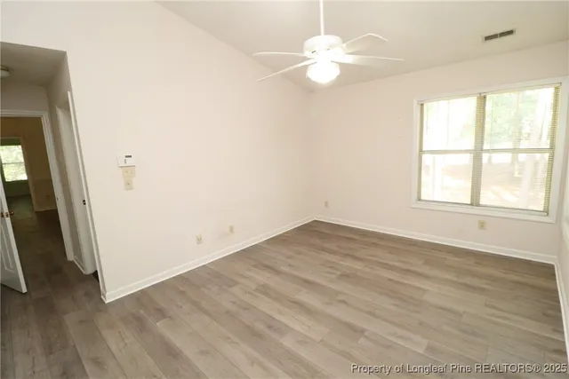 an empty room with wooden floor and window