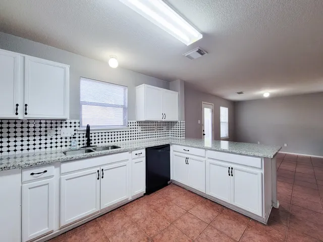 a kitchen with a sink dishwasher a stove and white cabinets