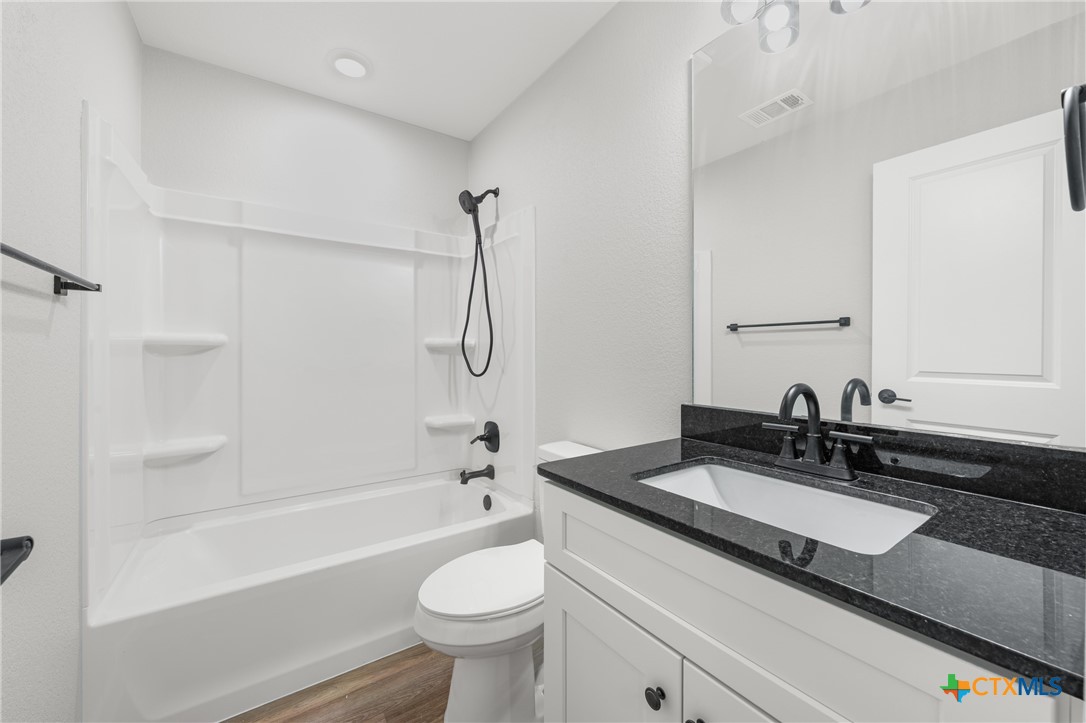 709 South 28th Street, Unit A Temple, TX 76501 - Photo 21 of 26 a bathroom with a granite countertop sink a toilet and shower