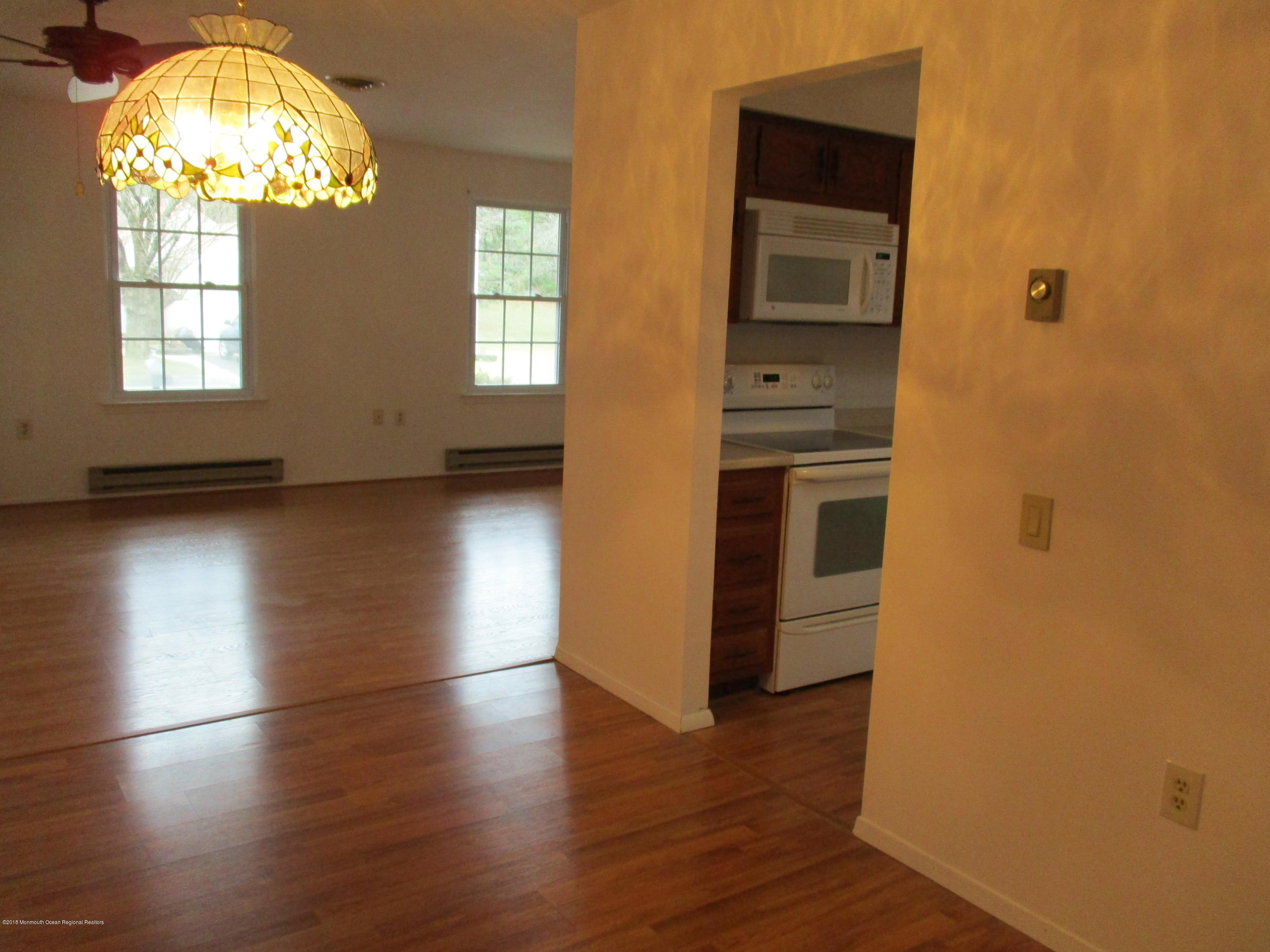 85 Sunset Road, Unit 60 Whiting, NJ 08759 - Photo 4 of 18 an empty room with wooden floor mirror and windows