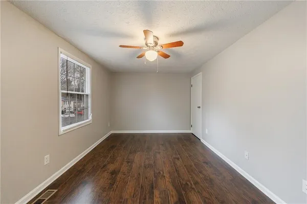 an empty room with wooden floor ceiling fan and windows