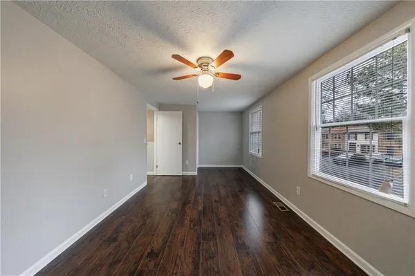 a view of an empty room with window and wooden floor