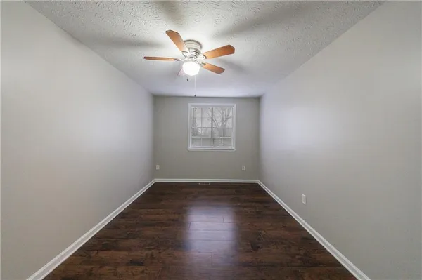 an empty room with windows and fan