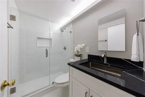 a bathroom with a granite countertop sink a toilet and shower