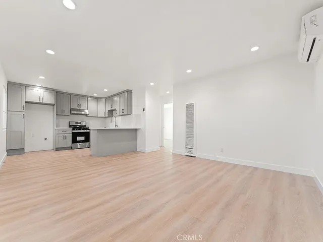 a view of kitchen with kitchen island a sink wooden floor and a refrigerator