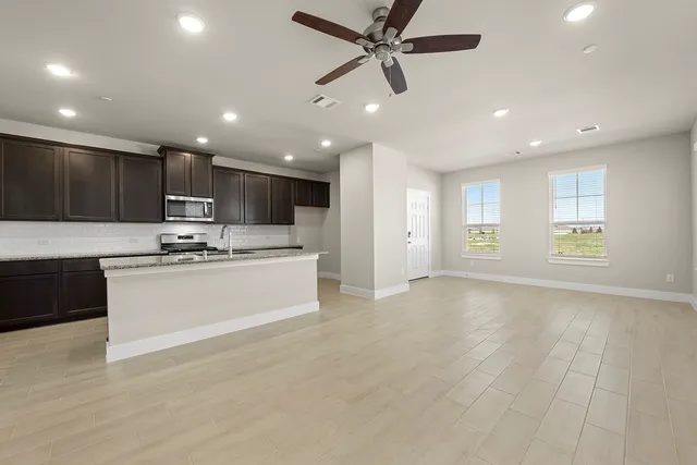a view of kitchen with kitchen island stainless steel appliances wooden cabinets and window