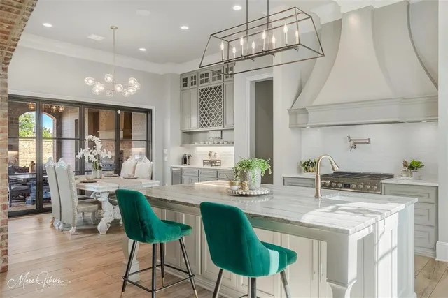 a kitchen with stainless steel appliances kitchen island granite countertop a dining table chairs and white cabinets